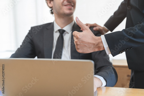 Close up view hand of boss encouraging employee by show thumb up after done good job