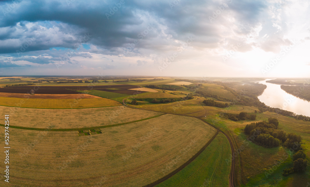Aerial drone view of river and wheat field landscape in sunny summer evening.