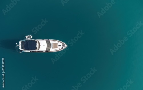 Aerial yacht on calm sea. Luxury cruise trip. View from above of white boat on deep blue water. Aerial view of rich yacht sailing sea. Summer journey on luxury ship.