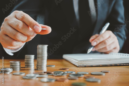businessman saving money concept. hand holding coins putting in jug glass, saving money with hand putting coins on stack concept financial.