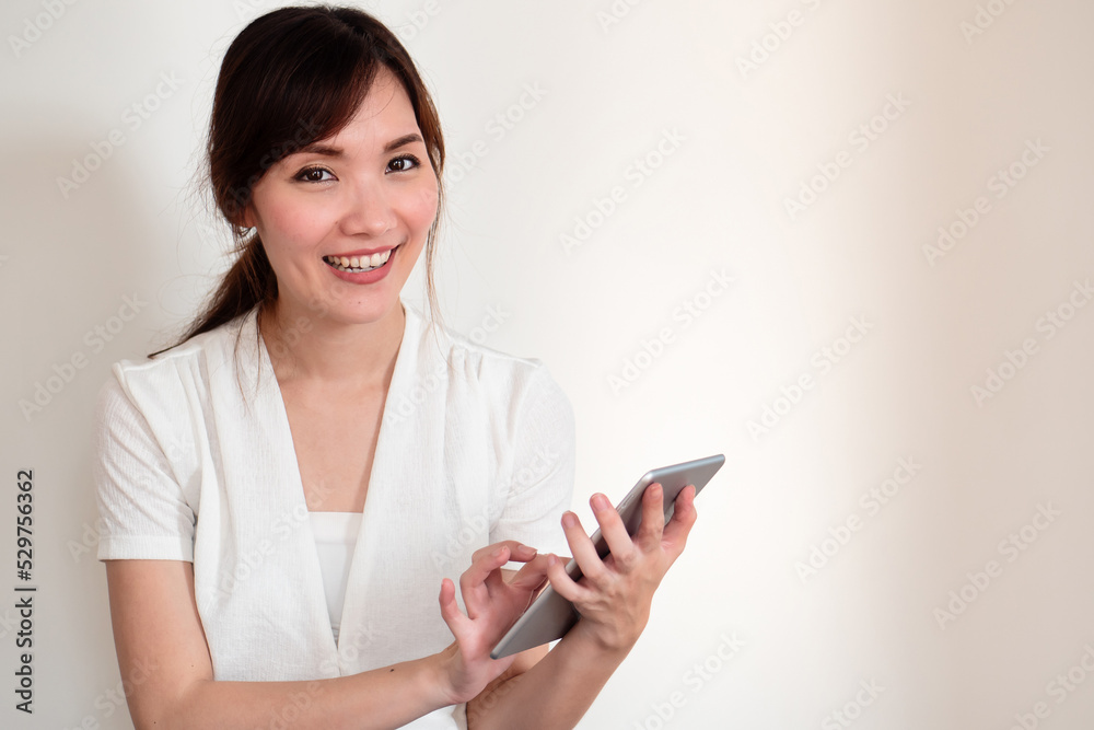 happy smiling young casual asian woman using computer tablet happy smiling young casual asian woman using computer tablet