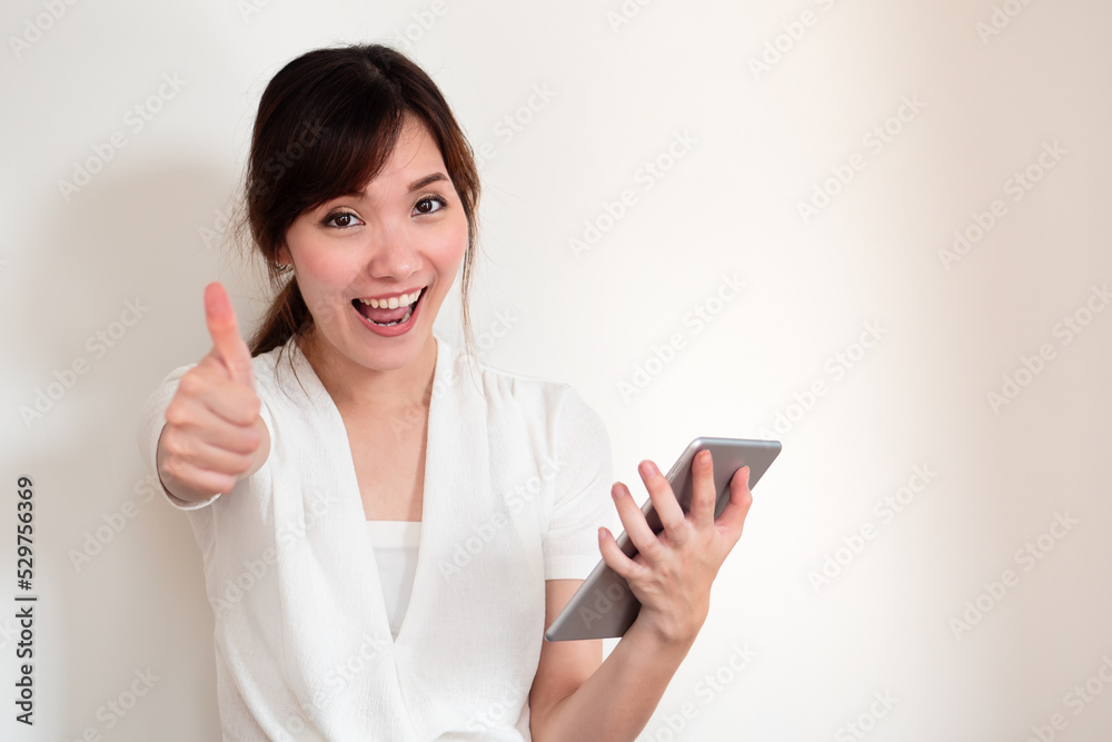 happy young casual asian woman using computer tablet showing thumb up gesture happy young casual asian woman using computer tablet showing thumb up gesture
