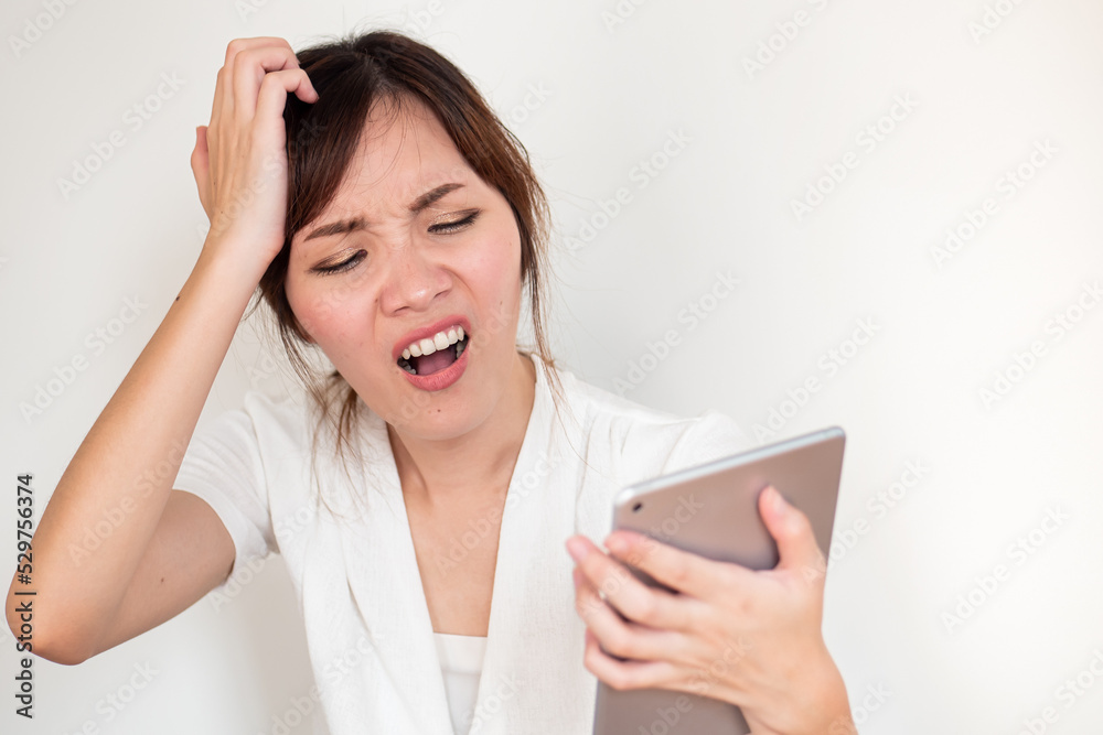 Upset angry asian woman using computer tablet showing negative disappointed expression Upset angry asian woman using computer tablet showing negative disappointed expression