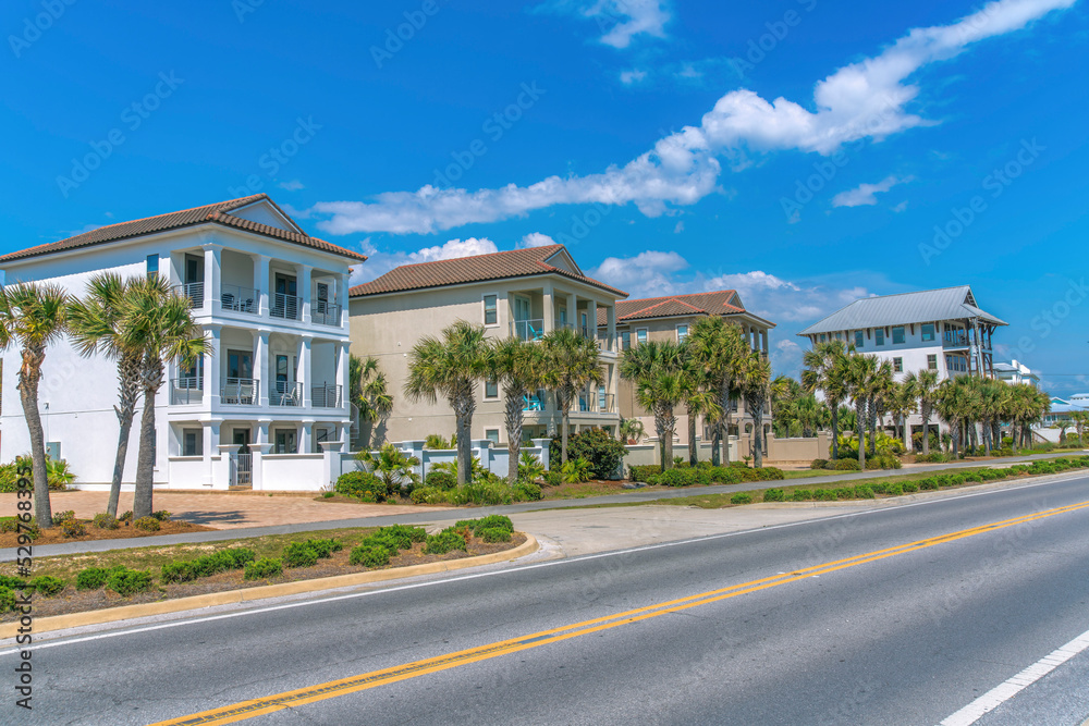 Three-storey beach houses with balconies and palm trees near a beach at Destin, Florida