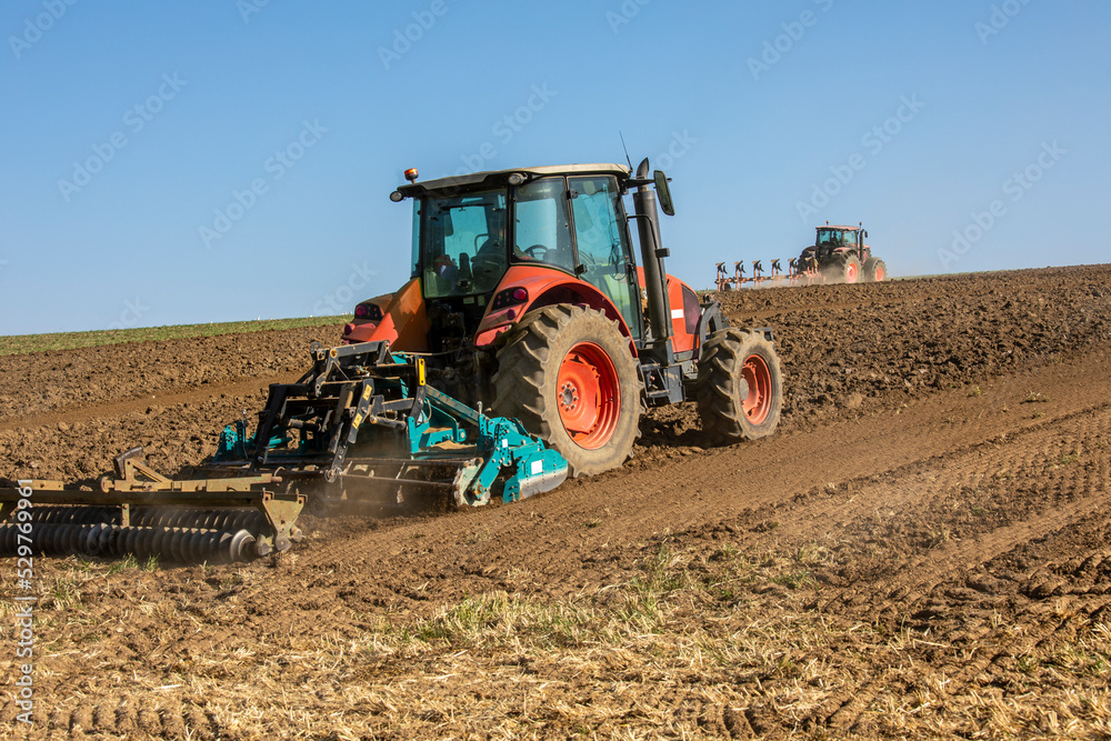 Fototapeta premium Agriculteur au volant de son tracteurs travaillant la terre au printemps.