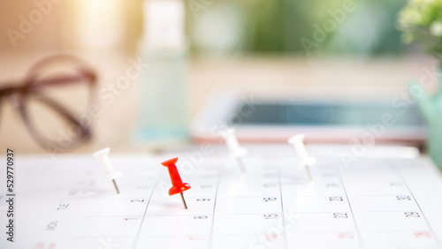 Close up pin on business desk calendar with office equipment concept of event planner or personal organization reminder and schedule or planning.
