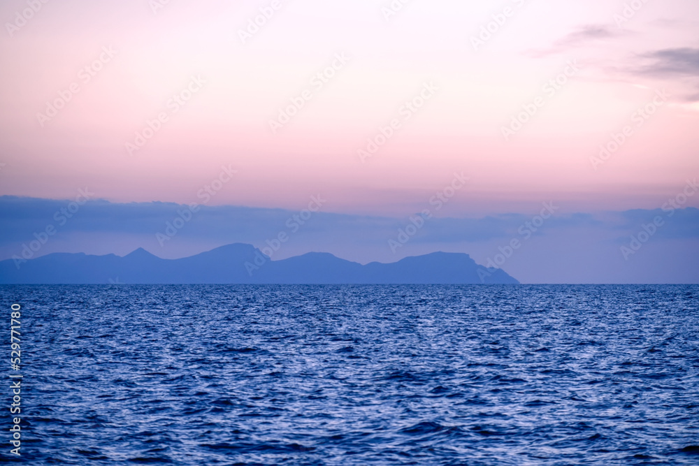 Sunset of ocean water with an island in the background