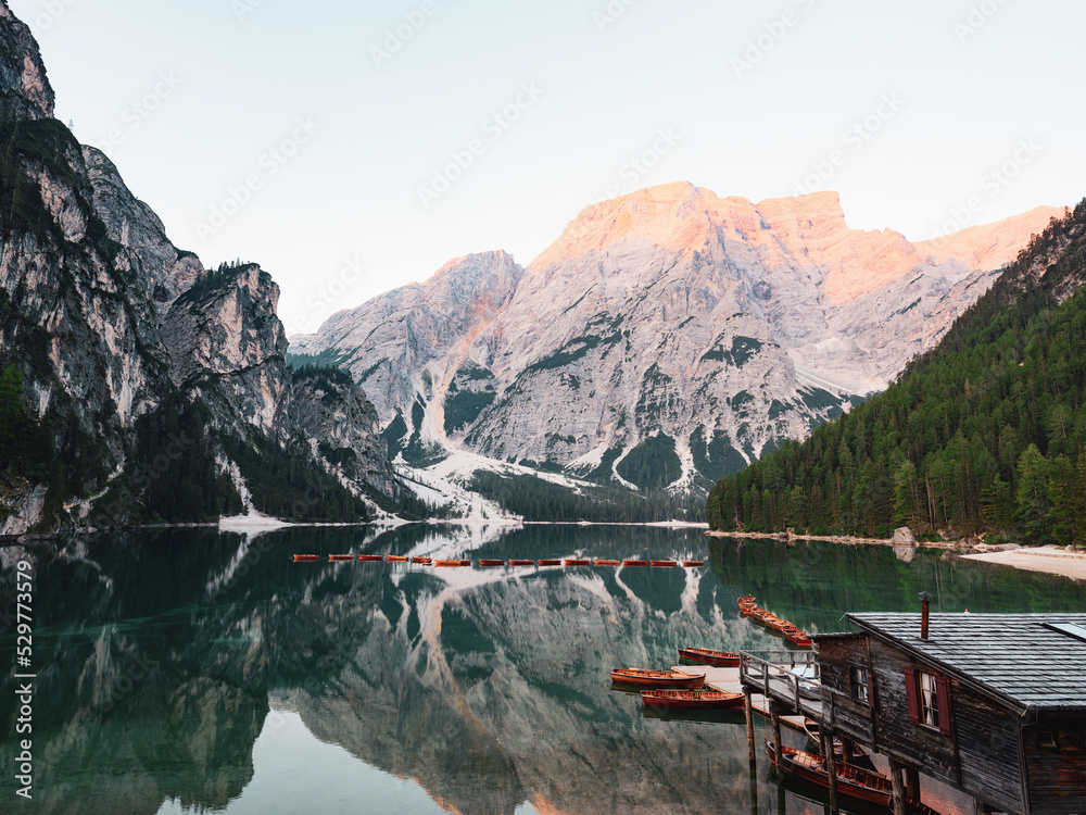 Stunning view of the Lake Braies (Lago di Braies, Pragser Wildsee) with some wooden boats and beautiful mountains reflected in the water. Lago di Braies is an alpine lake in the Dolomites, Italy