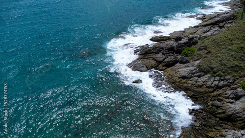 Fototapeta Naklejka Na Ścianę i Meble -  Aerial view of sea waves crashing on rocks cliff in the blue ocean. Top view of coastal rocks in Phuket ocean. Landscape view point of Laem Phromthep Cape in the morning.