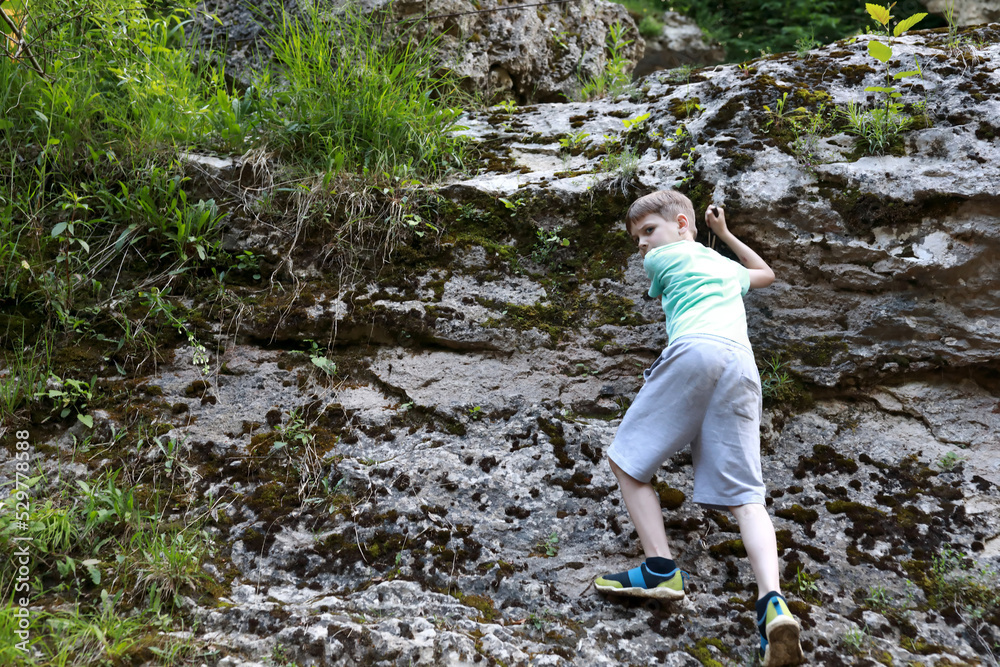 Child climbing rock in Khadzhokh gorge in summer