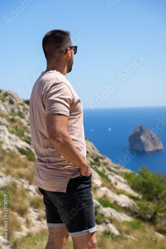 Unrecognizable young man on his back looking at the Mediterranean Sea in Mallorca, Spain.