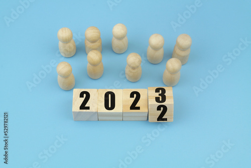 Wooden people figures and cubes with numbers 2022and 2023. People and economy in 2023 concept.