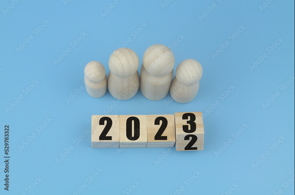 Family wooden figures and cubes with numbers 2022 and 2023 on blue background. Family wooden figures and cubes with numbers 2022 and 2023 on blue background.