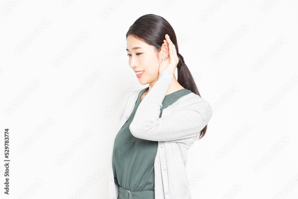 白背景の前で、聞き耳を立てている女性 白背景の前で、聞き耳を立てている女性