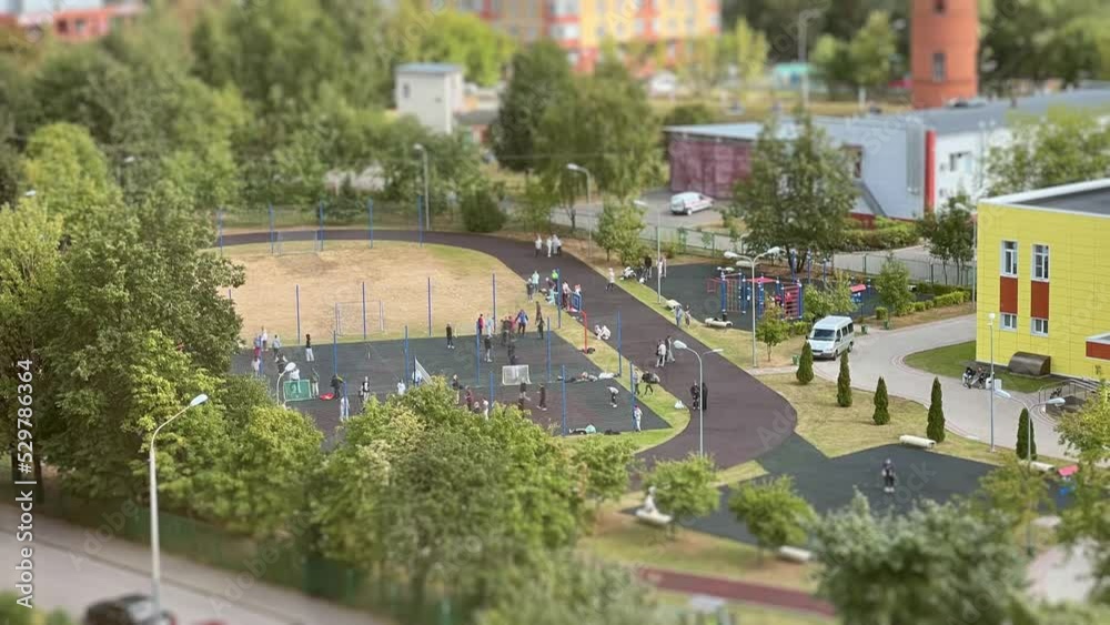 The motion activity of schoolchildren on the sports ground of the school stadium. High-angle view. Tilt-shift effect. Time Lapse The motion activity of schoolchildren on the sports ground of the school stadium. High-angle view. Tilt-shift effect. Time Lapse