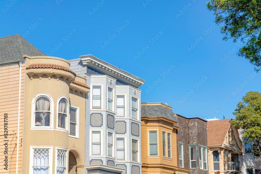 Fototapeta premium Row of houses with different structures against the clear blue sky in San Francisco, California