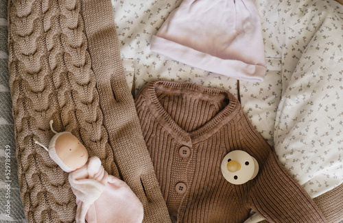 knitted brown baby romper and nipple, pink hat and toy on warm knitted blanket. autumn set of baby clothes. top view and flat lay