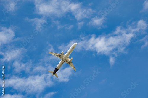 Landscape of airplane flying at low altitude at low angle, with blue sky background and clear of sunny day.