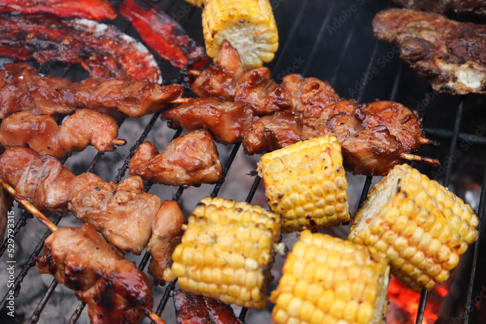South African braai with chicken kebabs, chops and mielies. Bacon rashers. shish kebab on skewers