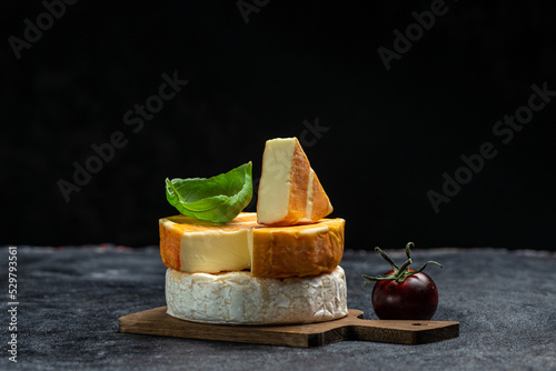 Set of Camembert, Brie, Gorgonzola blue cream cheese with basil leaves and cherry tomatoes on a dark background. Long banner format