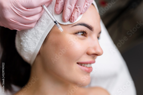 Принти на полотні Close up of hands of young cosmetologist injecting botox in female face