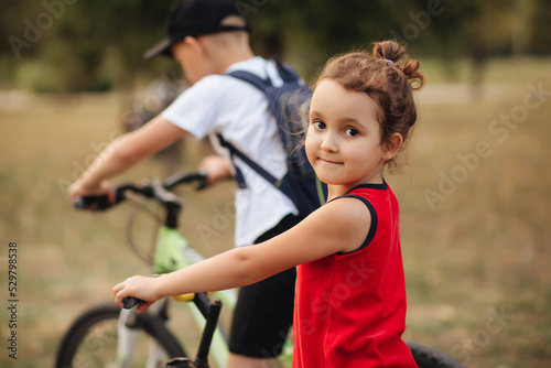 Two little boy and girl cyclists riding their bikes and enjoy having fun. Kid outdoors sport summer activity.