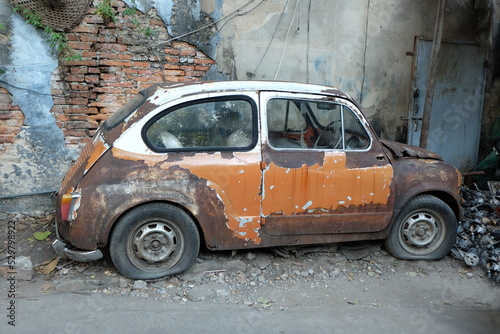 An old, rusty orange antique car that has been abandoned at Talat Noi, one of the oldest districts in Bangkok.