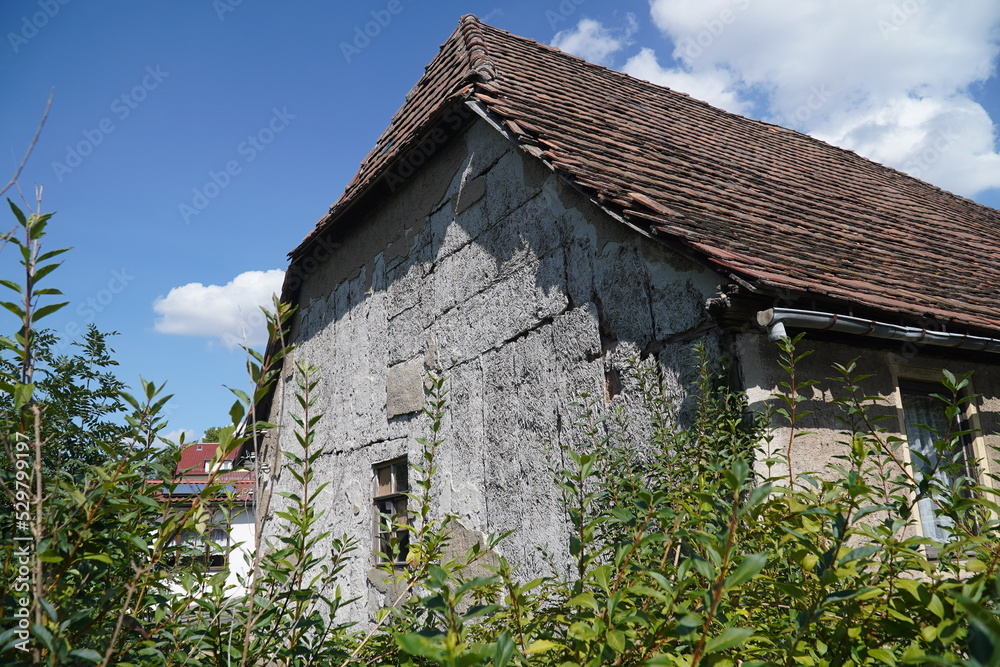 Dangerous asbestos on an old house facade. Old building material for wall coverings. This material is forbidden because of the risk of cancer from microfibers. Triptis Saale Orla, Thuringia, Germany