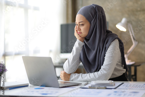 Muslim woman working on a laptop in the office is bored. Stress from working in the office.