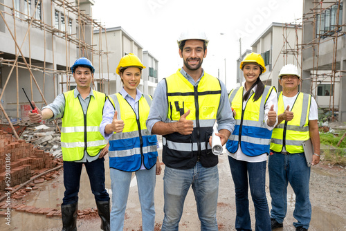 Chief engineer and foreman team celebrate residential project development success with smile at construction site. Group of successful construction workers enjoy working, and bonding with teamwork.