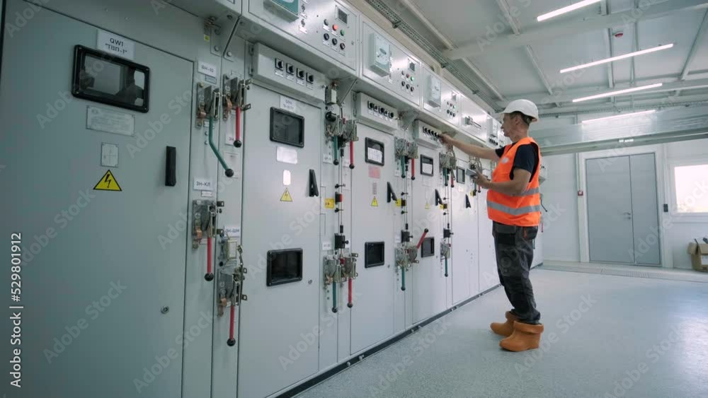 Electrical engineer working check the electric current voltage and overload at front of load center cabinet or consumer unit for maintenance in main power distribution system room.
