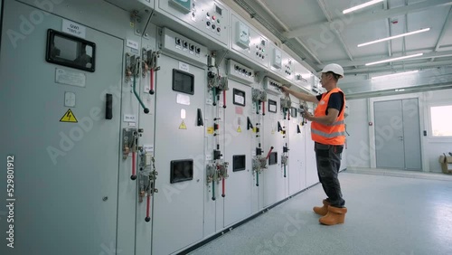 Electrical engineer working check the electric current voltage and overload at front of load center cabinet or consumer unit for maintenance in main power distribution system room.