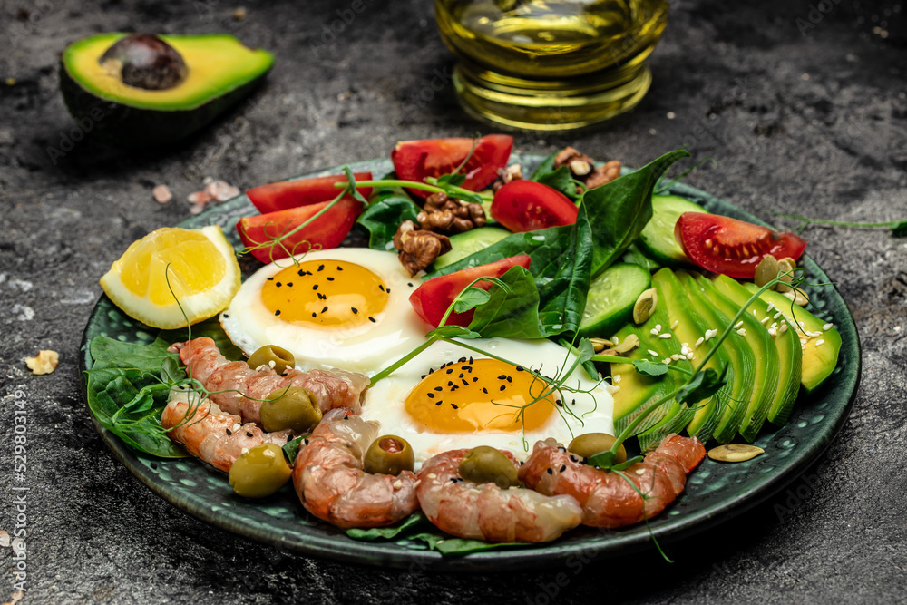 shrimps, prawns, soft fried egg, fresh salad, tomatoes, cucumbers and avocado on a dark background. Ketogenic diet breakfast. Keto, paleo lunch. Long banner format. top view shrimps, prawns, soft fried egg, fresh salad, tomatoes, cucumbers and avocado on a dark background. Ketogenic diet breakfast. Keto, paleo lunch. Long banner format. top view