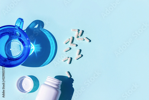 Pills and glass of water on blue background. Medicine, healthcare concept photo