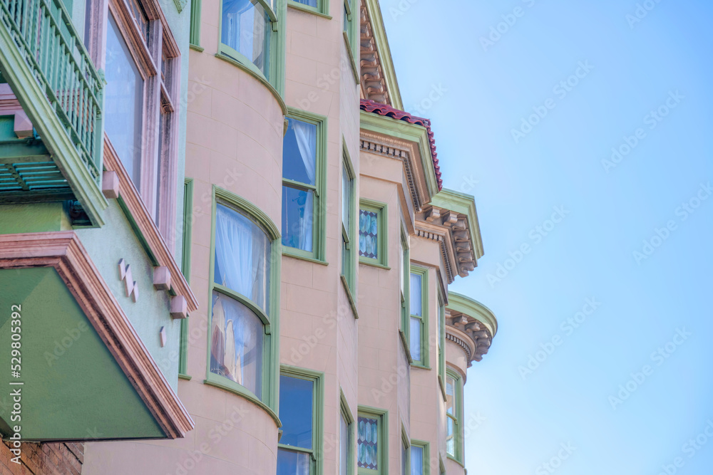 Apartment building with green window frames and corbel roof in San Francisco, CA