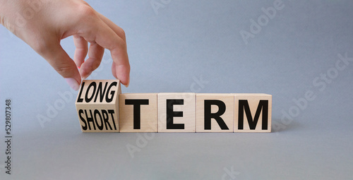 Long term vs Short Term symbol. Businessman hand turnes wooden cubes and changes words Short term to Long Term. Beautiful grey background. Business concept. Copy space. photo