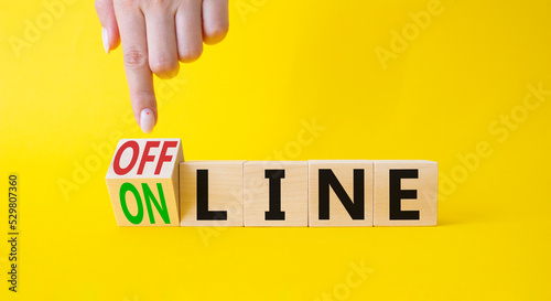 Offline and online symbol. Businessman hand points at turned wooden cubes with words Online and Offline. Beautiful yellow background. Business concept. Copy space. photo