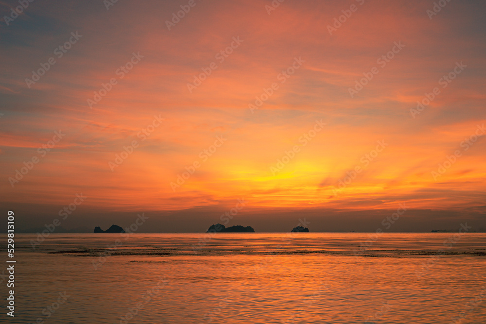 Colorful dramatic sky over the sea and islands. Reflections in the water.