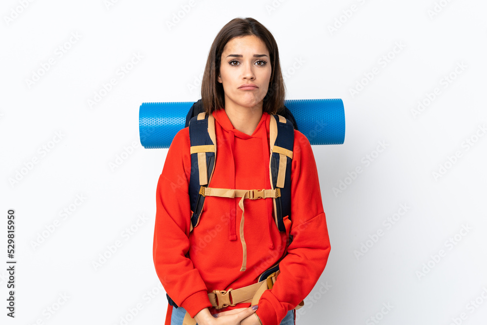 Young caucasian mountaineer girl with a big backpack isolated on white background sad Young caucasian mountaineer girl with a big backpack isolated on white background sad