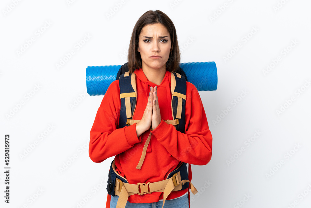 Young caucasian mountaineer girl with a big backpack isolated on white background pleading Young caucasian mountaineer girl with a big backpack isolated on white background pleading
