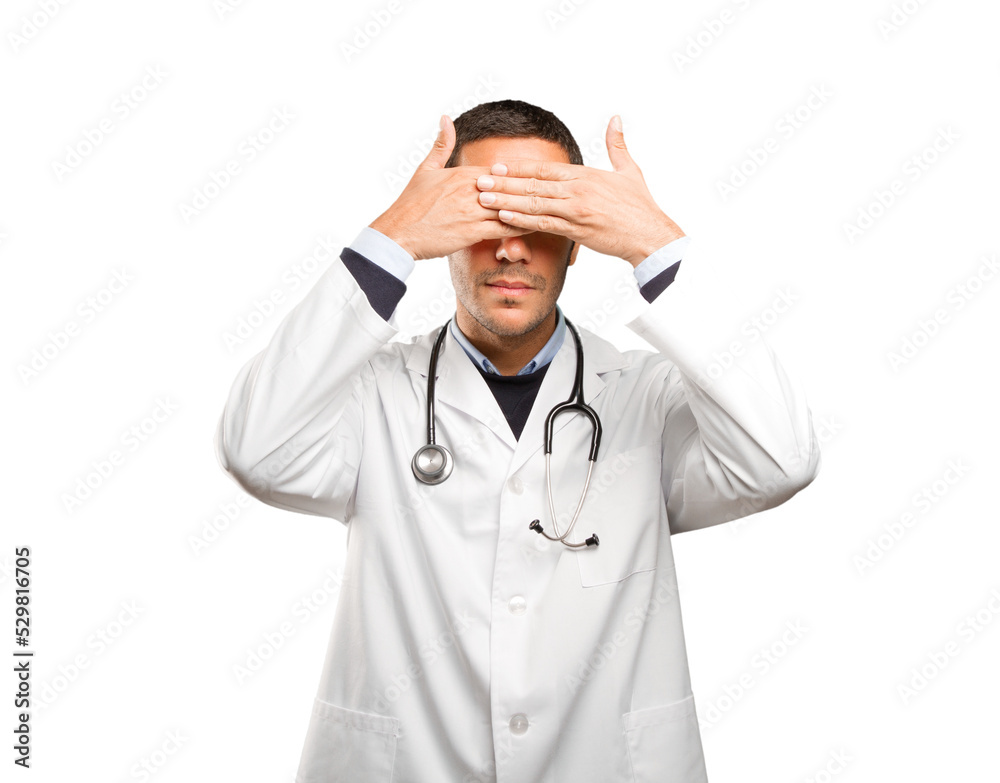 Scared doctor covering his eyes against white background Scared doctor covering his eyes against white background
