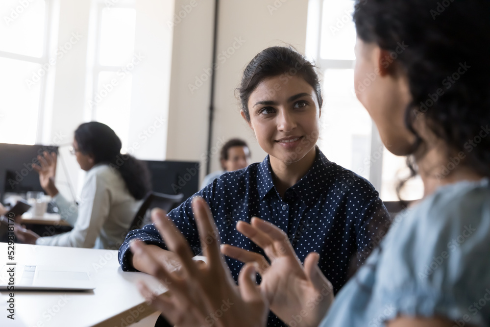 Φωτογραφία Happy Indian intern listening to mentor, consulting corporate teacher at shared office workplace in training center, discussing new professional skills, smiling