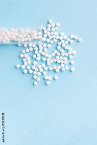 Homeopathic pills and a glass bottle on a blue background. Homeopathic medicine 