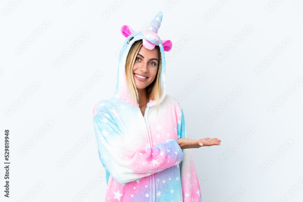 Blonde Uruguayan girl wearing a unicorn pajama isolated on white background presenting an idea while looking smiling towards