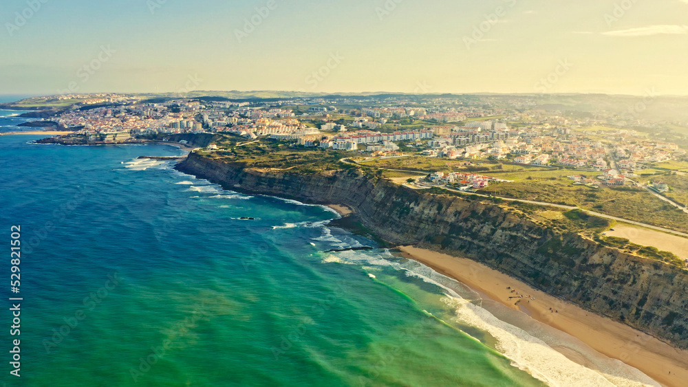 Drone view of a beautiful tourist town located on the shore of the Atlantic Ocean.  Panorama of the city from a drone with a  rocky ocean coastline during sunrise. Scenic summer  landscape  from drone