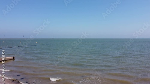 Drone rising over the ocean waves touching the shore under the blue sky photo