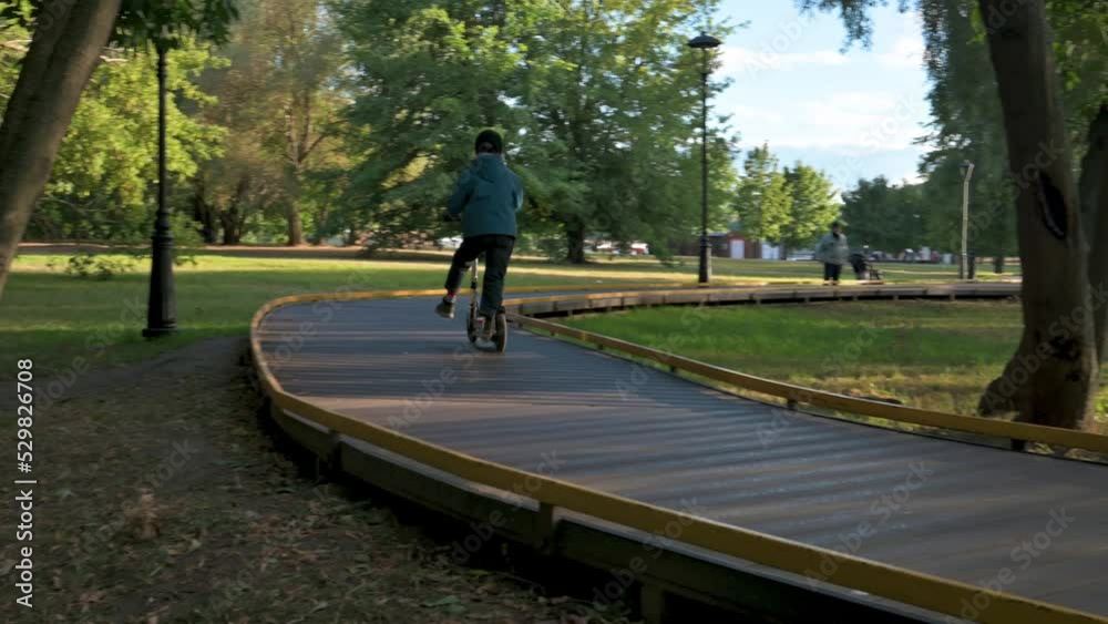Boy riding on kick scooter. Boy riding on bike path. 4k video footage UHD 3840x2160 Boy riding on kick scooter. Boy riding on bike path. 4k video footage UHD 3840x2160