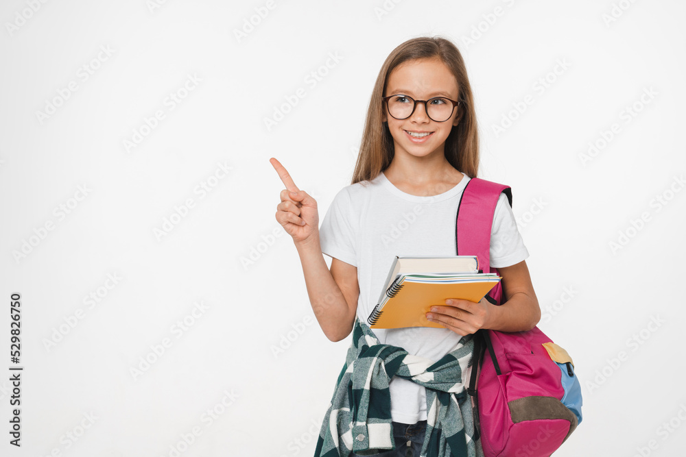 Small caucasian preteen teenage schoolgirl holding textbook preparing for new educational school year pointing at copyspace isolated in white background