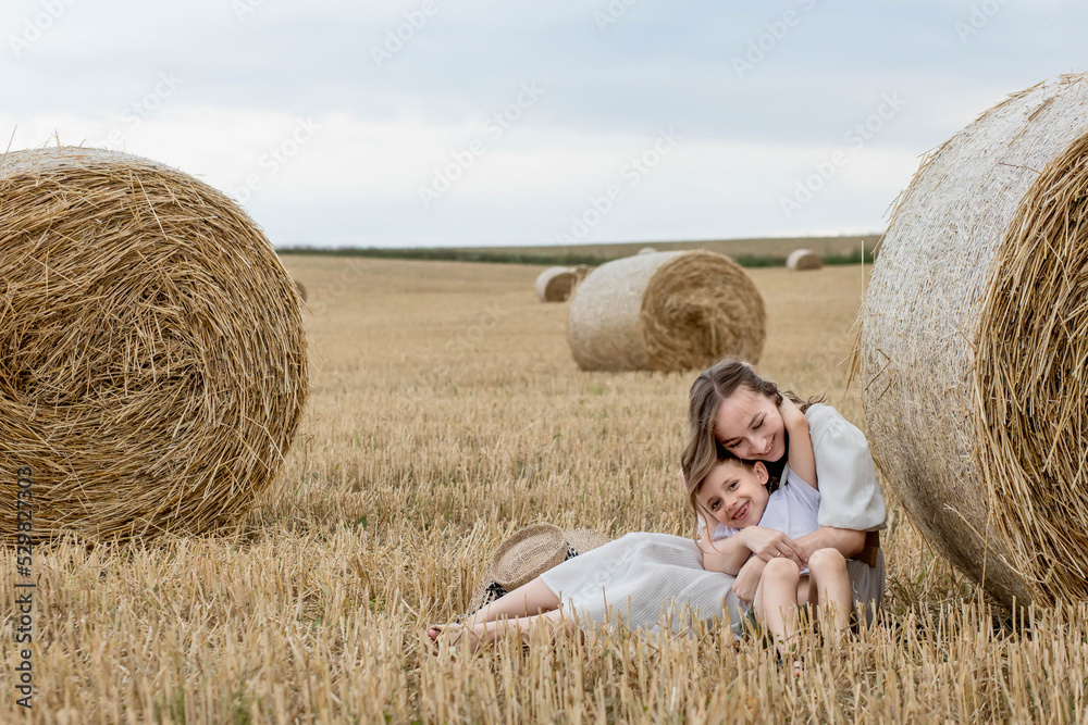 Young mother and her son are hugging near straw bales in a field. A happy family. Mother's day Young mother and her son are hugging near straw bales in a field. A happy family. Mother's day