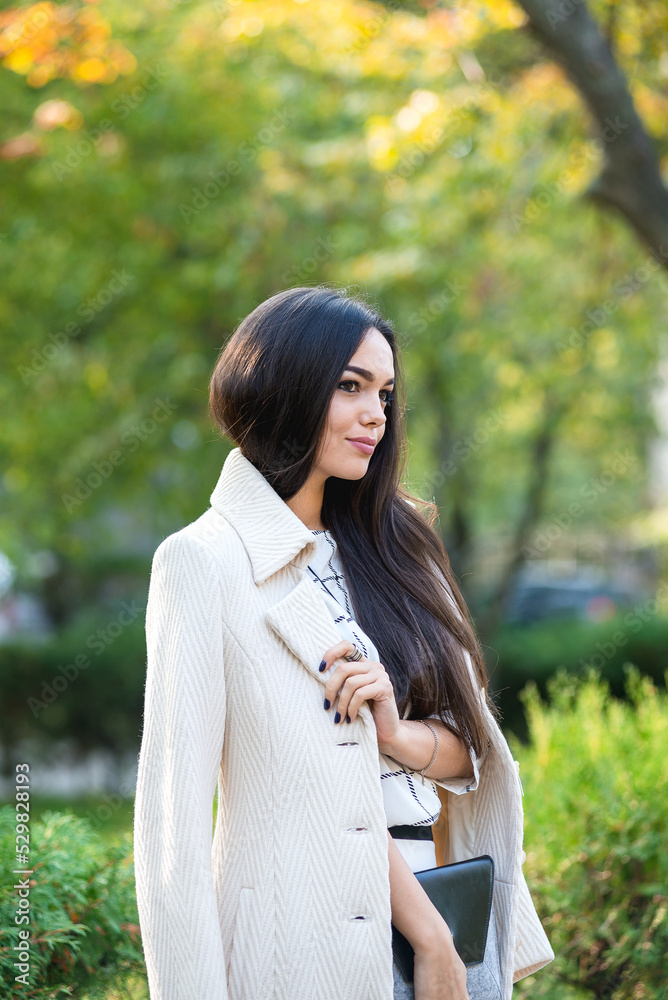 Young beautiful business lady is standing in the park in autumn. Young beautiful business lady is standing in the park in autumn.